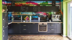 A modern kitchen with a herringbone wood floor, black cabinets, and a chalkboard menu listing prices for water, beer, wine, and coffee. - Das kleine Schwarze (Hamburg)
