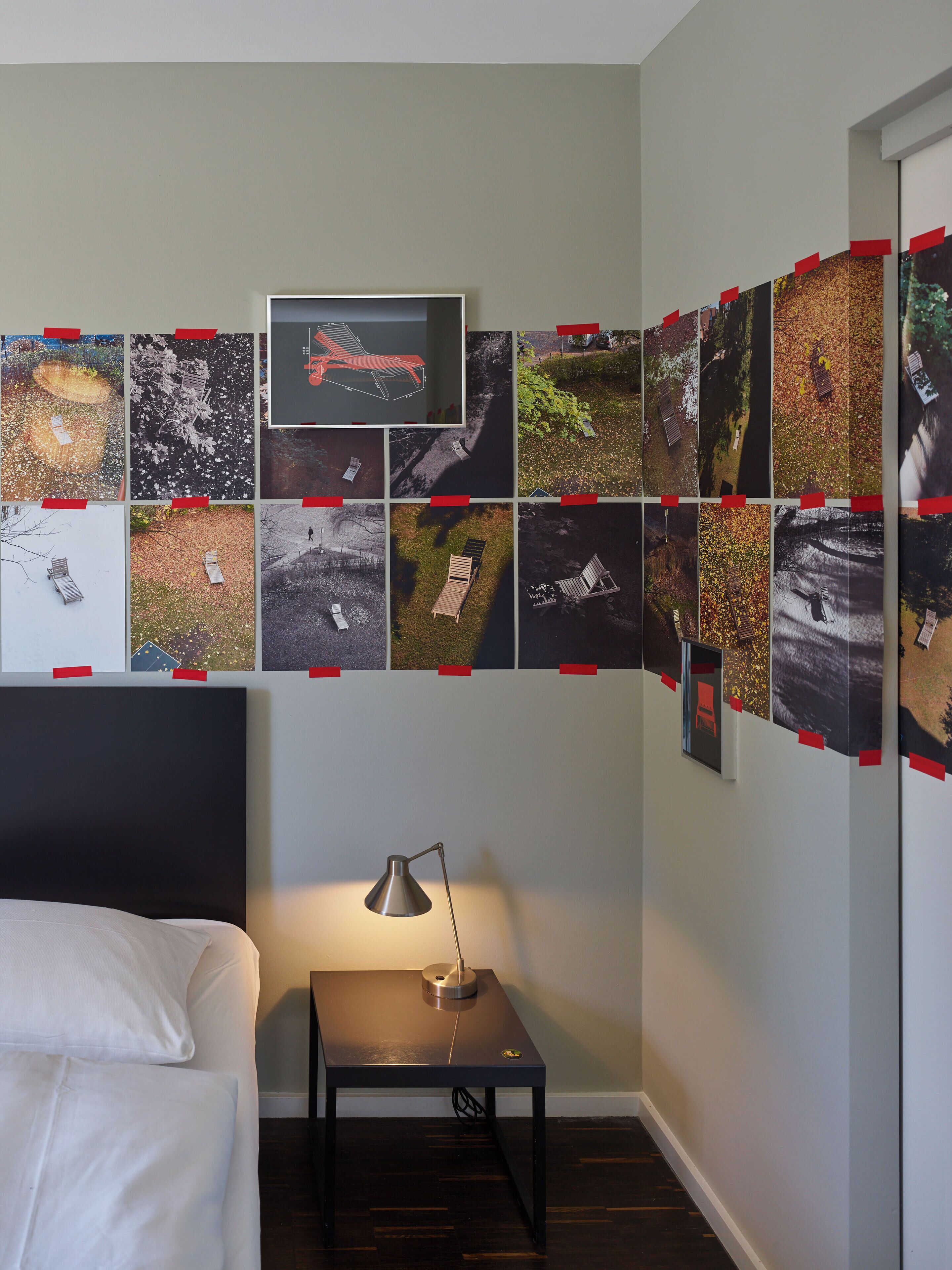 Une chambre d’hôtel avec un lit, un bureau doté d’une lampe et un mur décoré de photos.