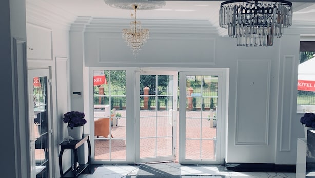 A spacious lobby with a marble floor, a chandelier, and a view of the outdoor area through glass doors. - Monte Carlo Boutique Hotel (Swinoujscie)
