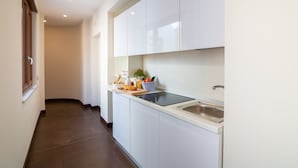 A modern kitchen with white cabinets, a built-in stove, and a sink. - Il Melograno Relais (Vico Equense)