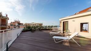 A wooden deck with white railings, two white lounge chairs, and a small table with a chair. - Il Melograno Relais (Vico Equense)