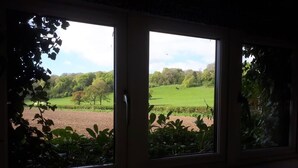 A room with a large window overlooking a green landscape. - Grandwood House (Chichester)