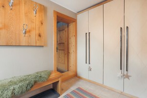 Una habitación con un banco de madera, un armario de dos puertas y un espejo.