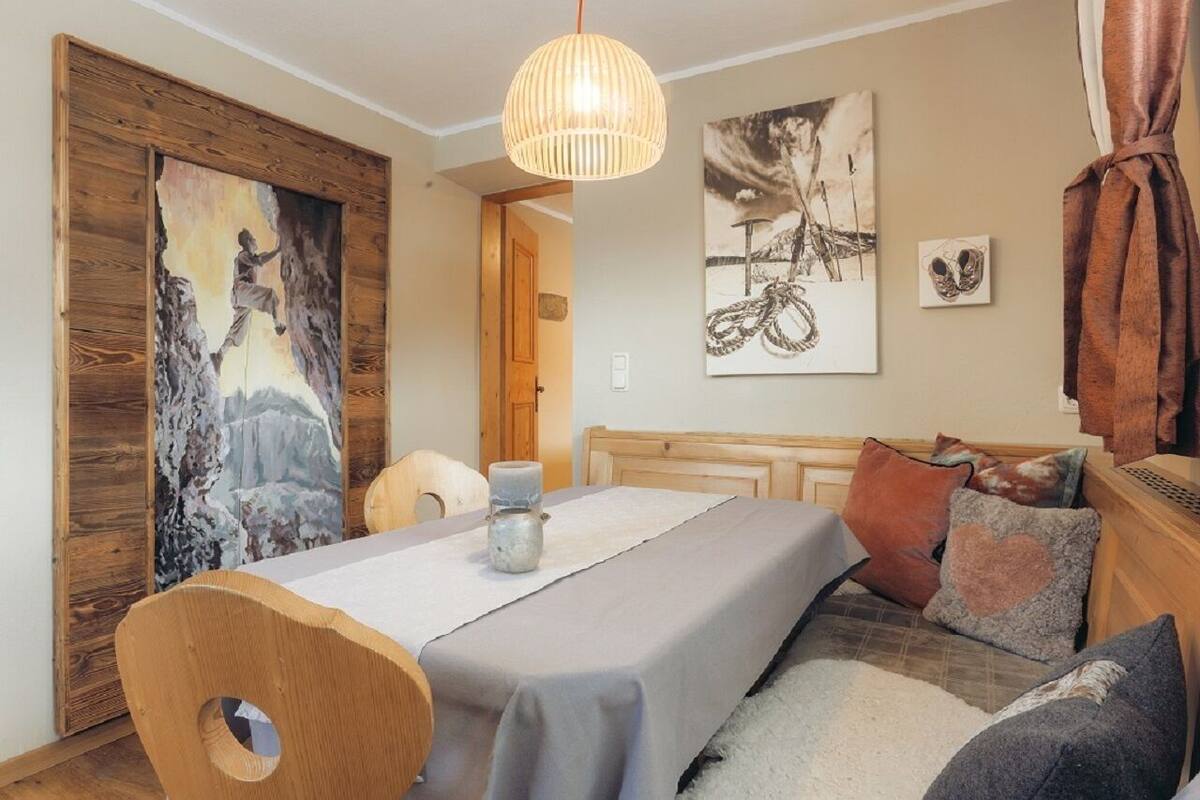 A cozy room with a wooden dining table, a sofa, and a painting of a mountain scene.