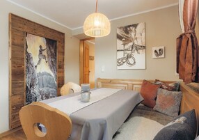 Una habitación acogedora con una mesa de comedor de madera, un sofá y un cuadro de un paisaje montañoso.