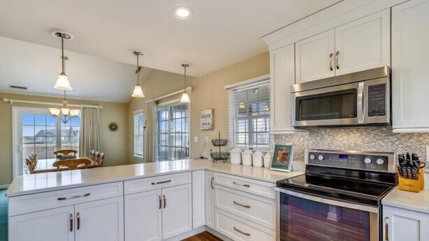 A kitchen with white cabinetry, stainless steel appliances, and a large island. - Chapman - 2 Blocks to Beach Access - Resort Amenities (Duck)