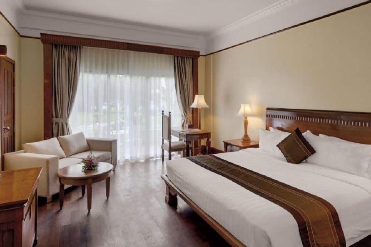 A hotel room with a large bed, a sofa, a desk, and a chair.