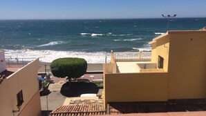 Une vue sur la côte, avec un balcon donnant sur la mer, un petit arbre et un toit recouvert de tuiles.