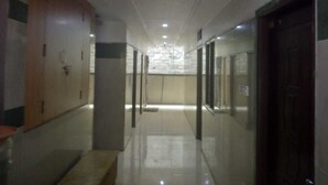 A corridor with lockers, a bench, and a door on the right. - iROOMZ Pranathi Comforts (Ballari)