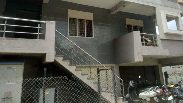 A building named "Prathithi Comfort" with a staircase leading to an upper floor, a gated entrance, and a parked scooter. - iROOMZ Pranathi Comforts (Ballari)