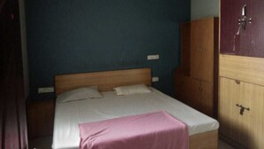 A bedroom with a bed, a wooden wardrobe, and a ceiling fan. - iROOMZ Pranathi Comforts (Ballari)