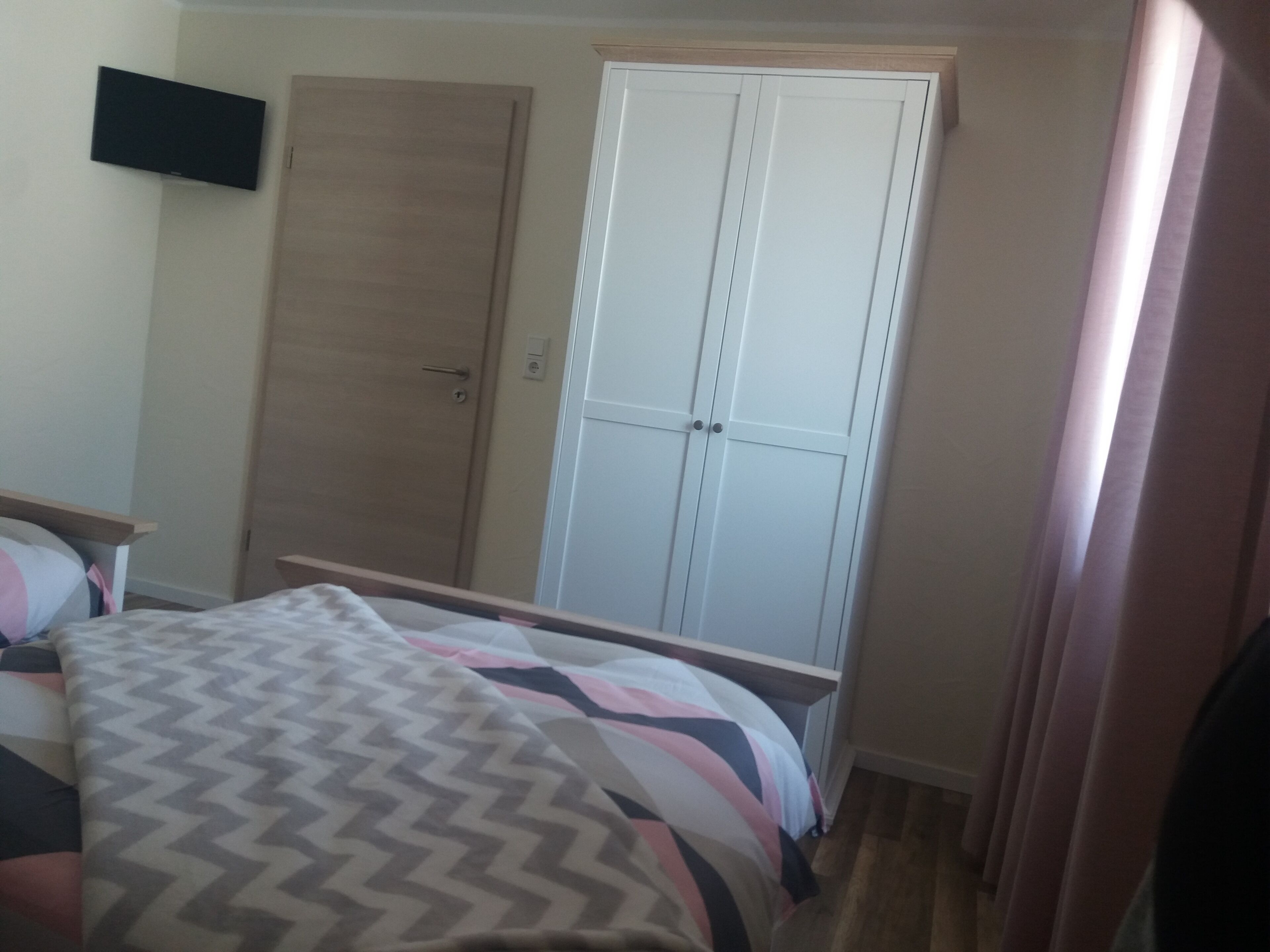 Une chambre à coucher avec un lit, une armoire et un téléviseur fixé au mur.