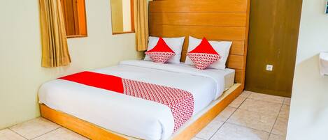 A neatly made bed with a wooden headboard, a red and white patterned blanket, and matching pillows.