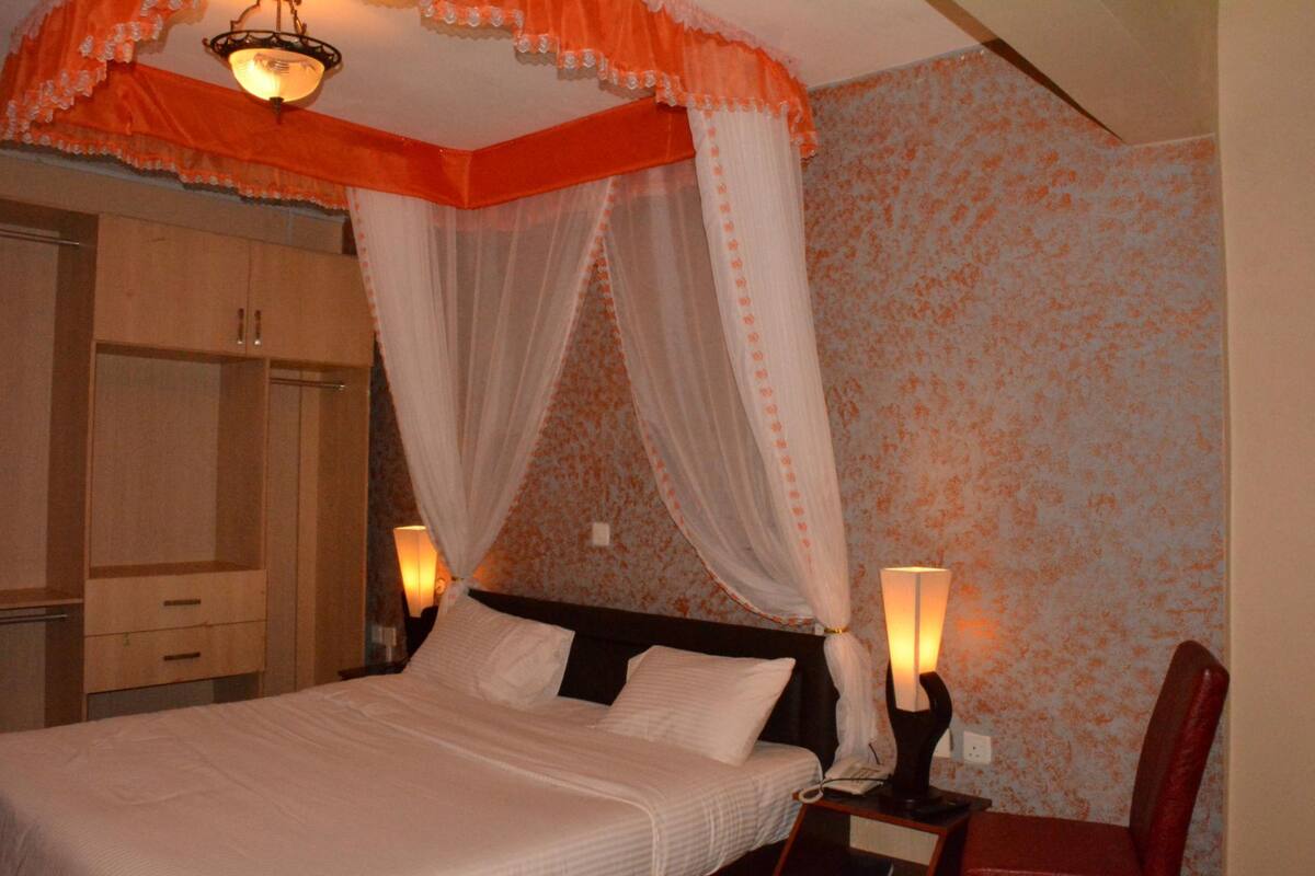 Un dormitorio con cama a dosel, lámparas de noche y un armario.