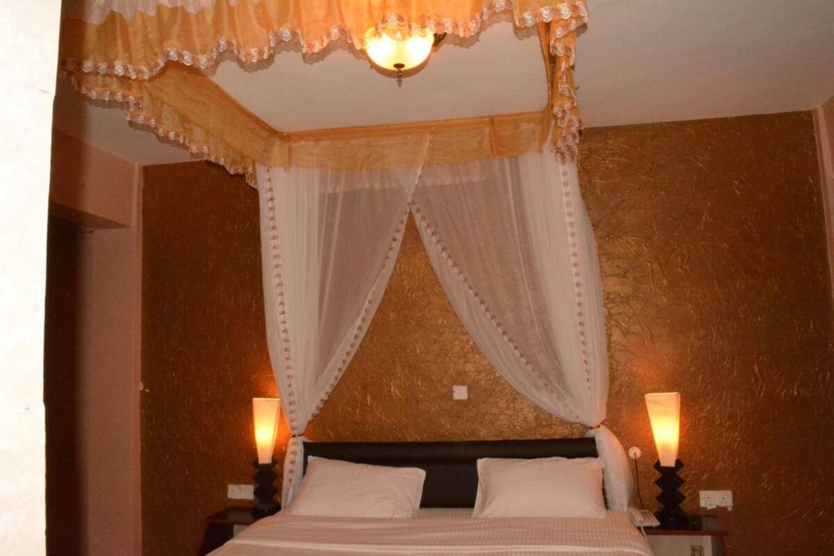 Una cama con dosel, dos lámparas de noche y una pared con textura.