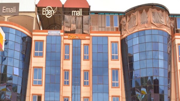 A multi-story building with large glass windows, a sign for Eden mall, and a sign for Eden hotel. - Eden Hotel Emali (Emali)