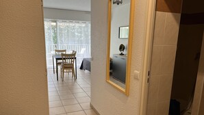 Un pasillo con suelo de baldosas, un espejo en la pared y vistas a un comedor con sillas y una mesa.