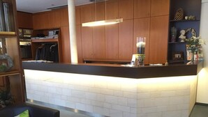 A modern kitchen with wooden cabinets, a black countertop, and a white tiled backsplash. - Hotel Kronprinz (Kulmbach)