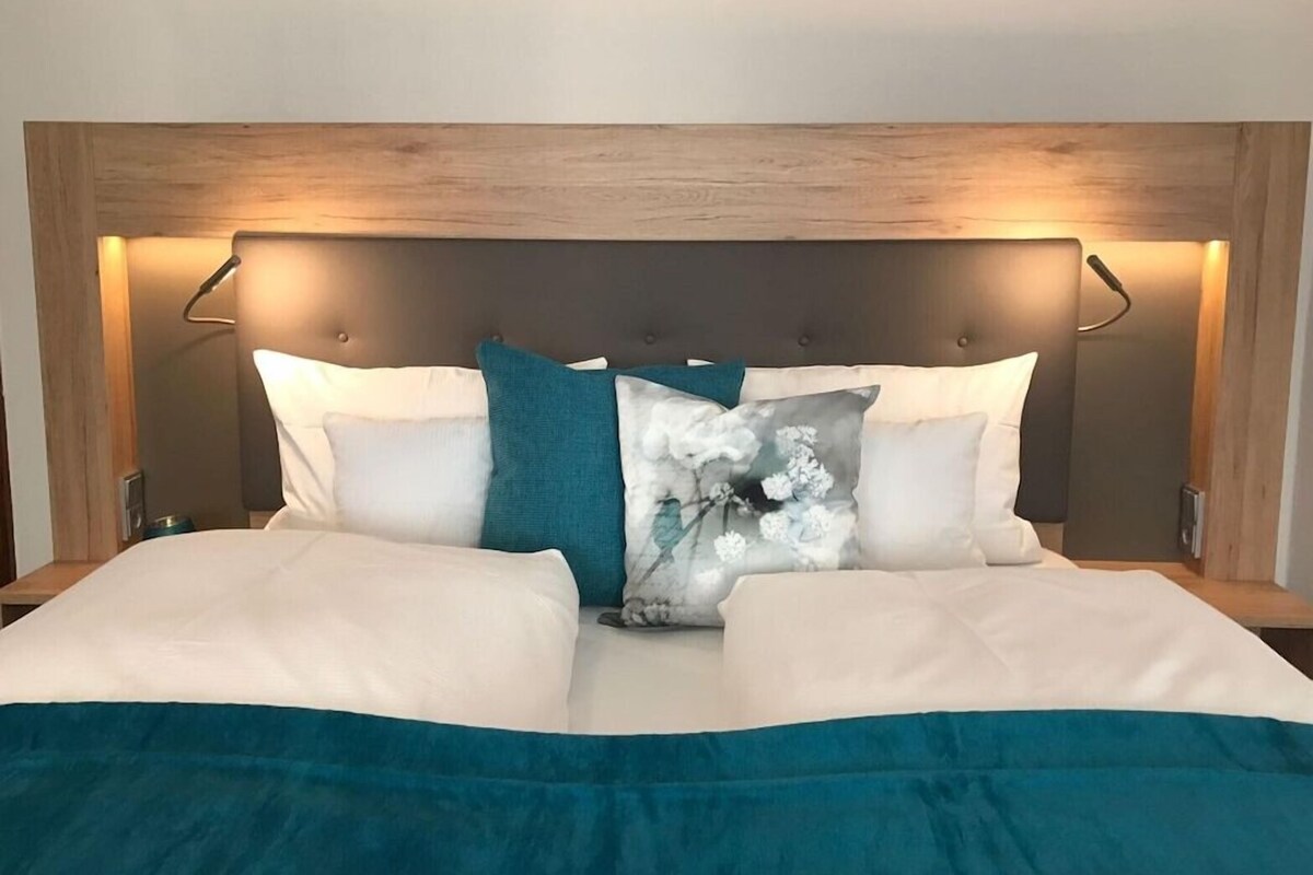 A bed with a headboard, two bedside tables, and a blue blanket.