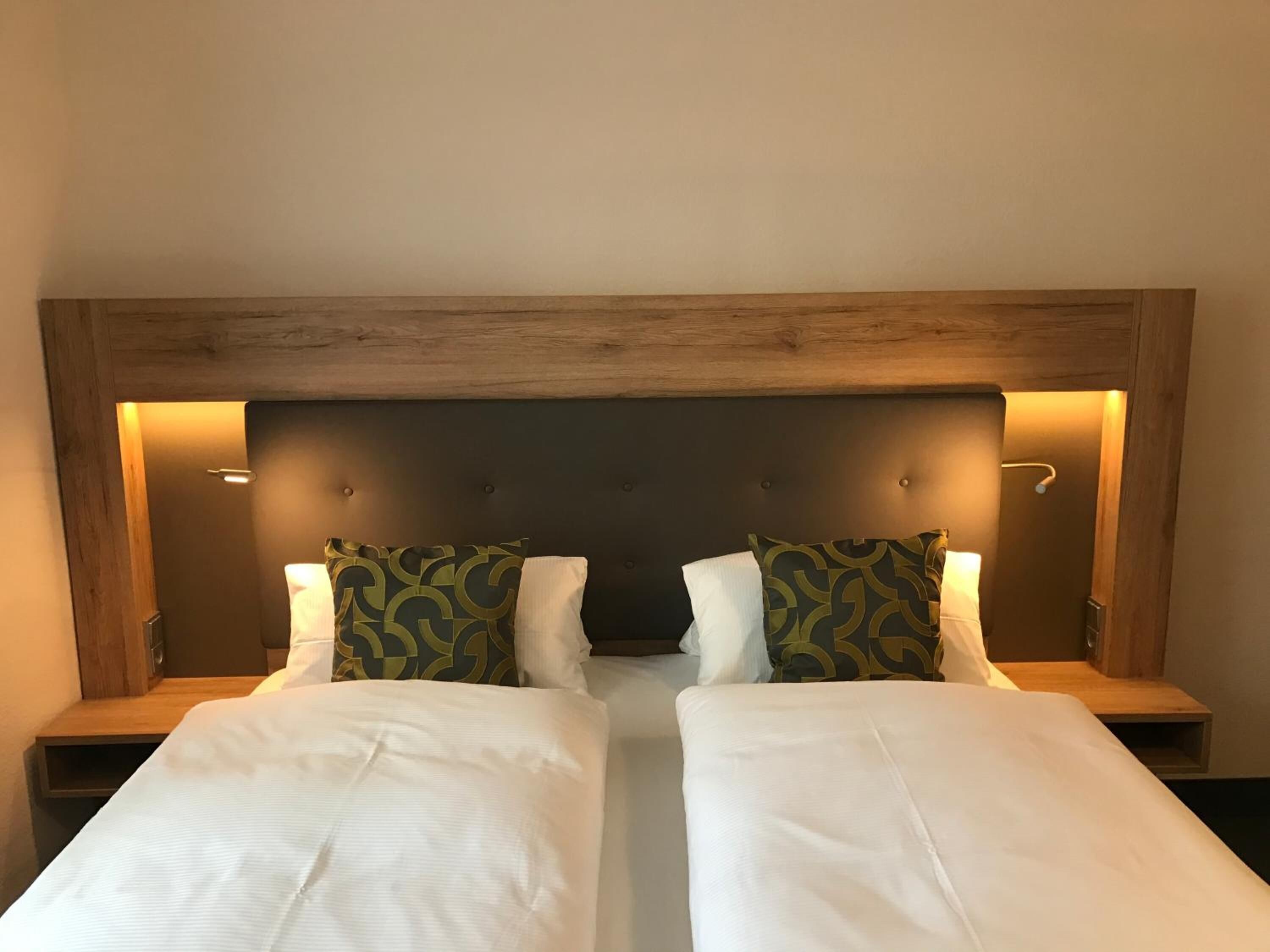 Ein Doppelbett mit Holz-Kopfteil und zwei Nachttische mit Lampen.