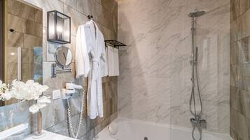 Une salle de bain moderne avec un mur en marbre, une baignoire, une douche, un meuble-lavabo avec un miroir et un porte-serviettes.