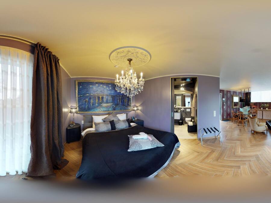 Een moderne hotelkamer met een groot bed, een kroonluchter, een schilderij en uitzicht op de badkamer.