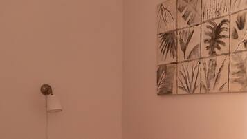 A bedroom with a bed, a wall-mounted light, and a wall art piece.