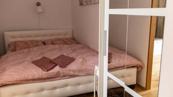 Een slaapkamer met een bed, een wandlamp en een deur.
