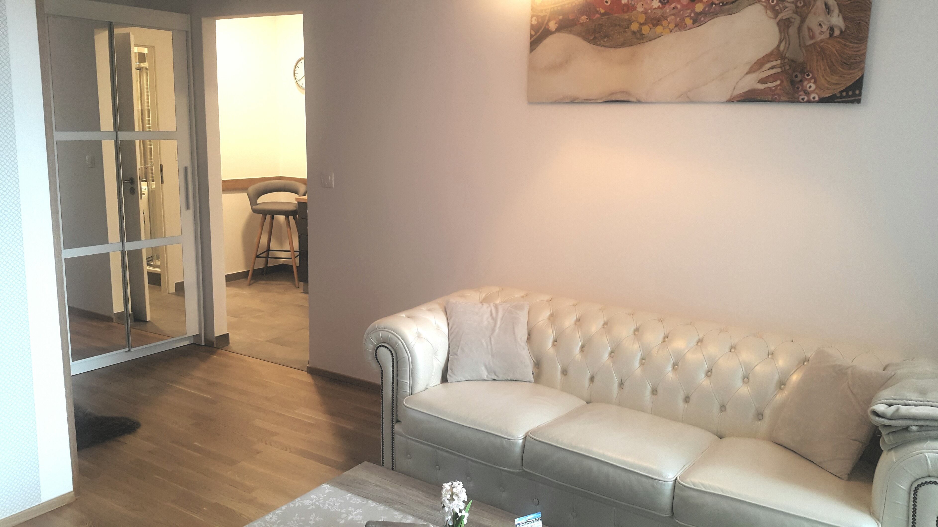 Una sala de estar con un sofá de cuero blanco, una mesa de centro y un cuadro en la pared.