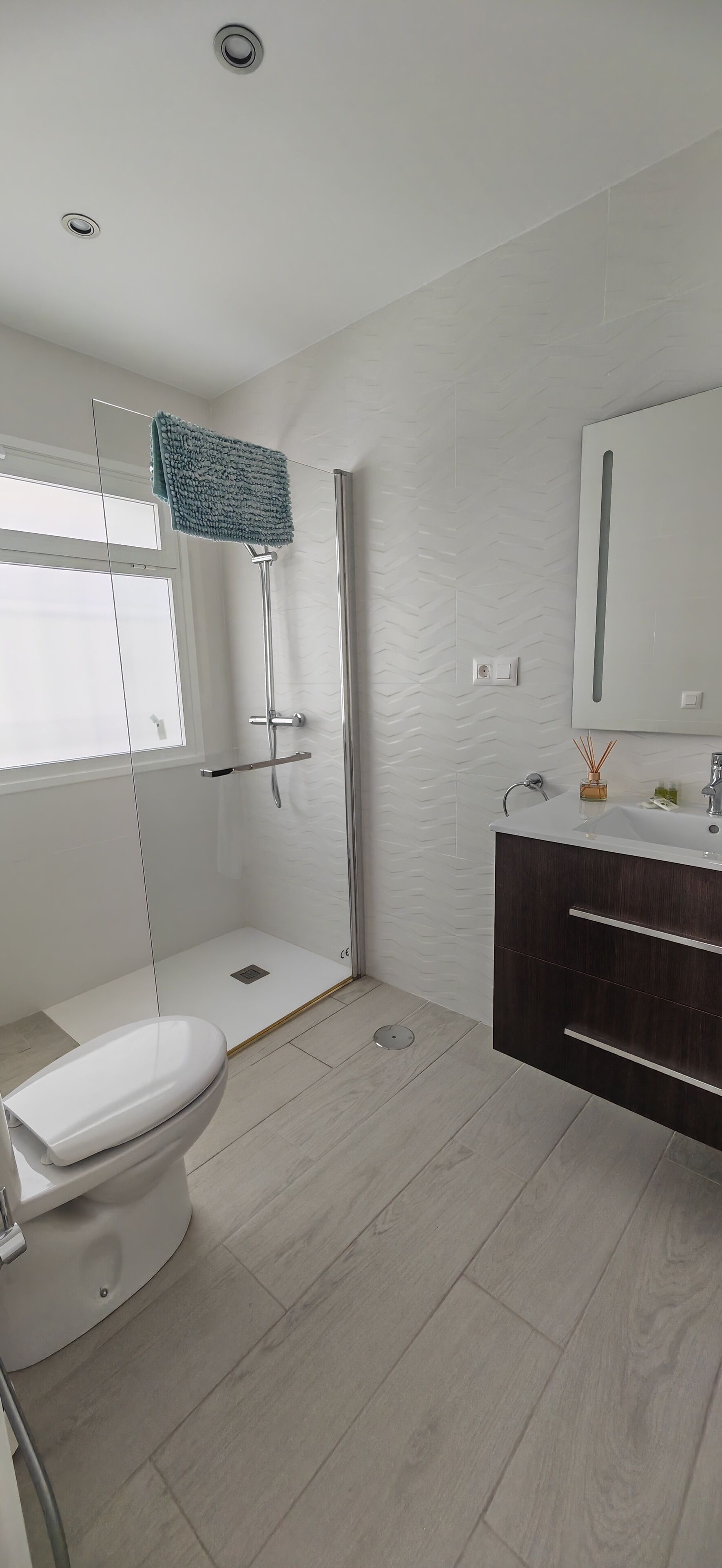 A modern bathroom with a toilet, shower, and vanity.