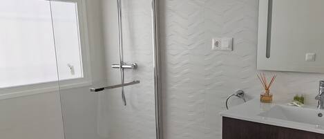 A modern bathroom with a toilet, shower, and vanity.