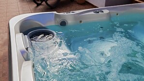Un jacuzzi con agua, un patio con sillas y un edificio al fondo.