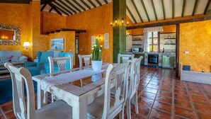 Un vaste espace de vie comprenant un coin repas avec une table et des chaises, et une cuisine en arrière-plan.