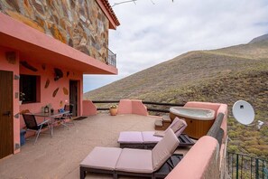 A cozy outdoor patio with lounge chairs, a hot tub, and a dining area with a table and chairs. - Apartamento Vulcano - Two Bedroom Apartment, Sleeps 3 (Adeje)