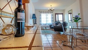 Un salon avec un canapé, une table en verre et une bouteille de vin.