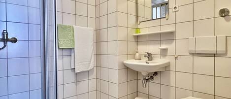 Un baño con lavamanos blanco, inodoro y zona de ducha.