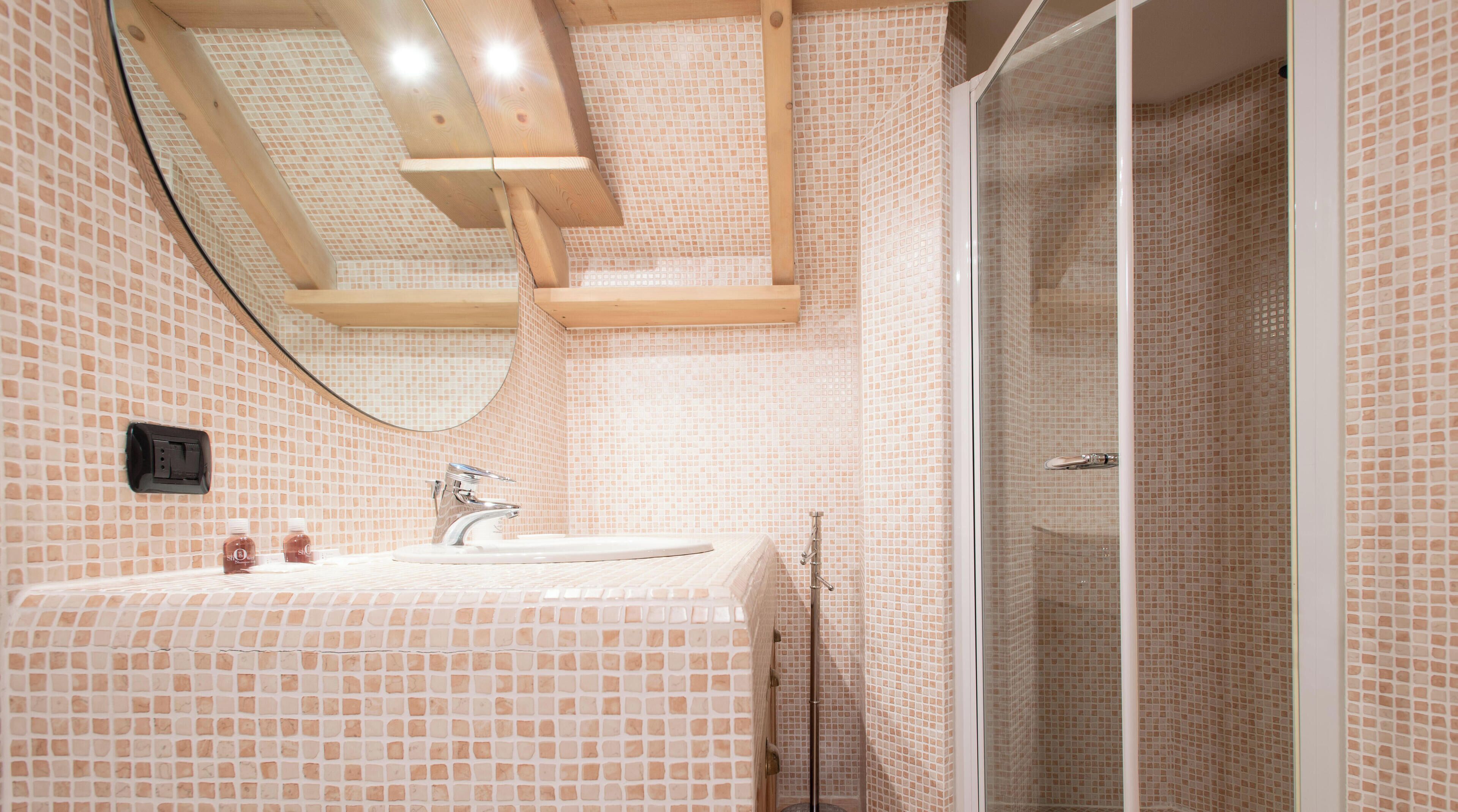 Une salle de bain avec un mur carrelé, un lavabo, un miroir et un espace douche.