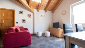 Quarto moderno com teto de madeira, sofá vermelho, armário de madeira com televisão e uma janela.