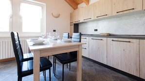Une cuisine moderne avec des meubles en bois, une table à manger pour quatre personnes et un pare-feu en pierre.
