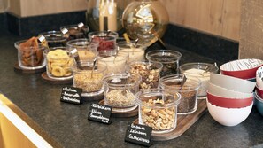 Diversos alimentos expuestos en recipientes transparentes con etiquetas que identifican diferentes tipos de nueces y cereales.