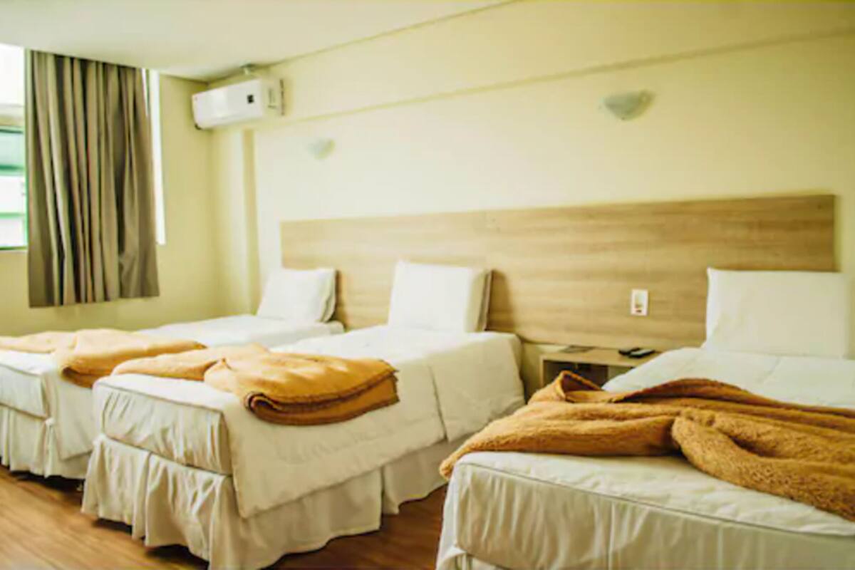 A hotel room with two beds, a wooden headboard, and an air conditioning unit on the wall.