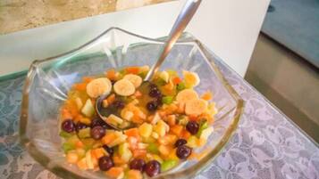 Uma tigela de vidro com salada de frutas e uma colher.