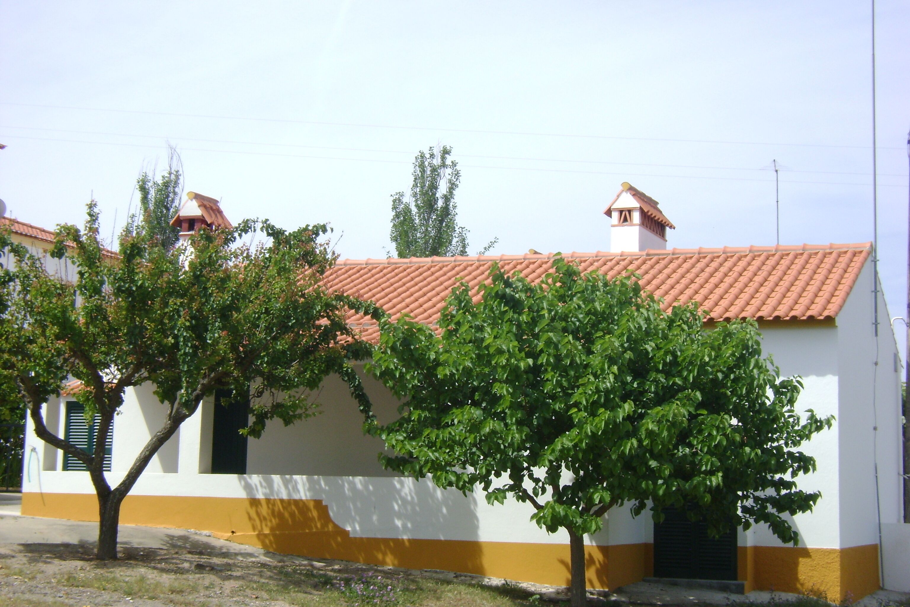Un edificio con tejado de tejas rojas y fachada amarilla y blanca.
