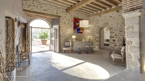 Un hall amplio con pared de piedra, techo de madera y un gran arco que da al exterior.