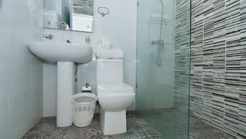 Un baño moderno con lavamanos, inodoro y ducha.