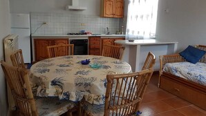 Ett kompakt kök med en matplats, med kakel som stänkskydd, träskåp och ett litet fönster med gardiner.