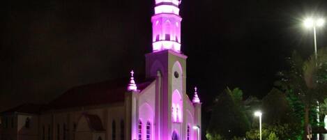 A church with a prominent bell tower and arched windows, illuminated at night.