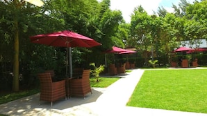 A pathway lined with red umbrellas and wicker furniture, leading to a grassy area. - The Noble Hotel and Conference Center (Eldoret)