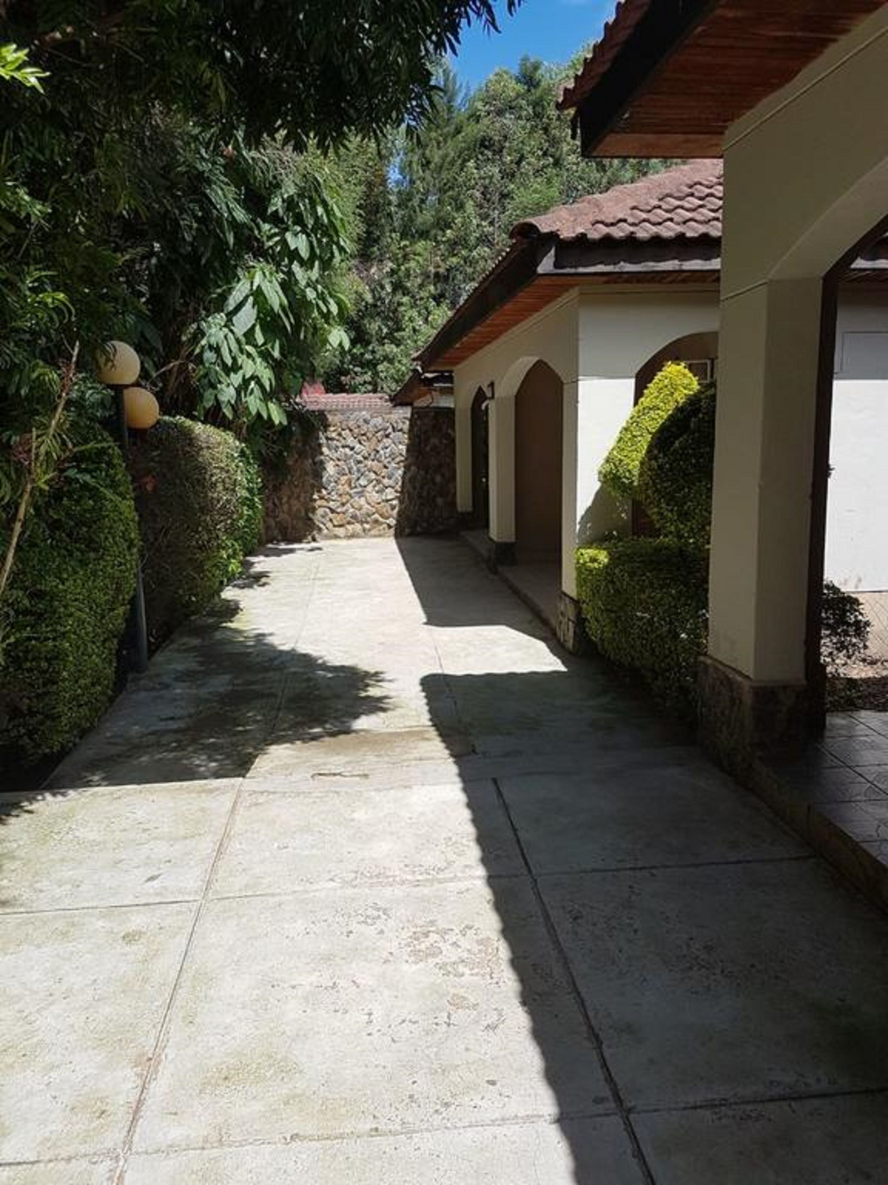 A paved pathway leading to a building with a tiled roof and stone walls.