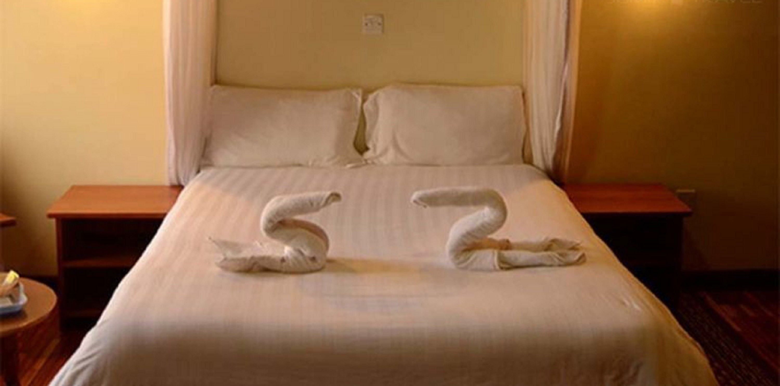Une chambre d’hôtel avec un lit, deux tables de chevet et un rideau.